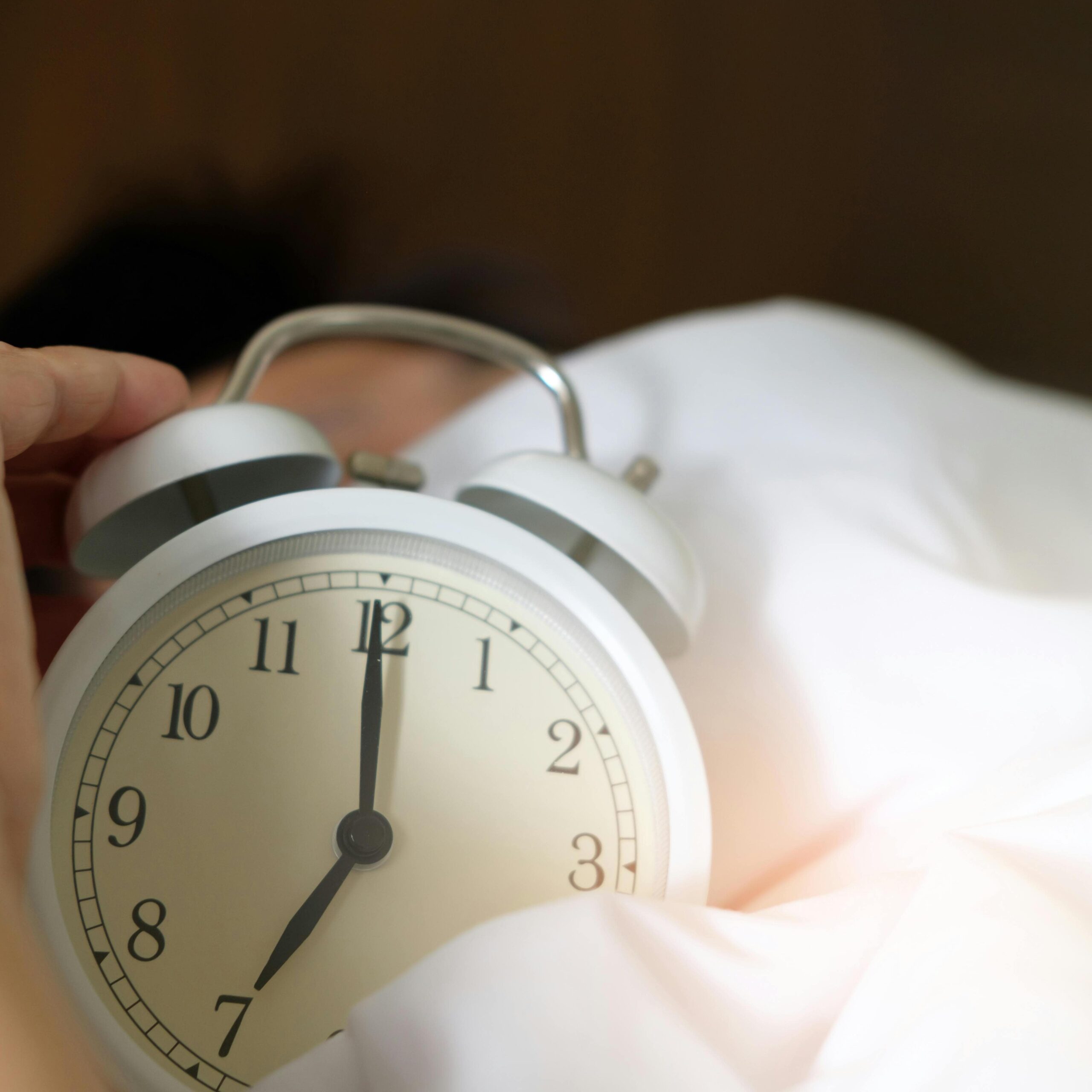 An alarm clock next to someone resting